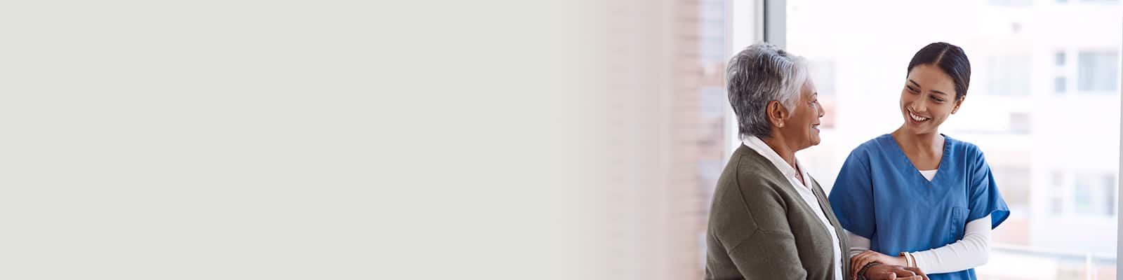 A caregiver talking to an elderly resident at a window