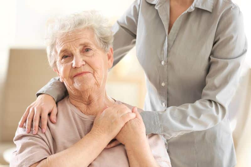 Older woman being embraced by family member with arms around her